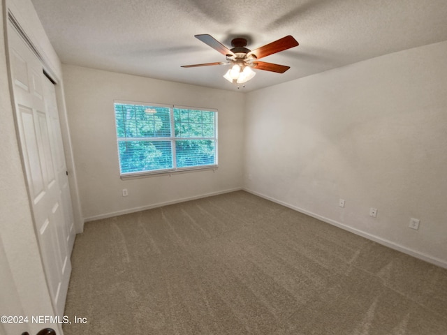 unfurnished bedroom featuring ceiling fan, carpet flooring, a closet, and a textured ceiling