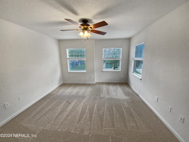 carpeted empty room with ceiling fan and a textured ceiling