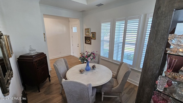 dining area featuring wood-type flooring and crown molding