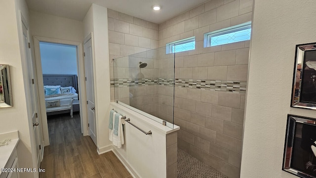 bathroom featuring a tile shower, vanity, and hardwood / wood-style flooring