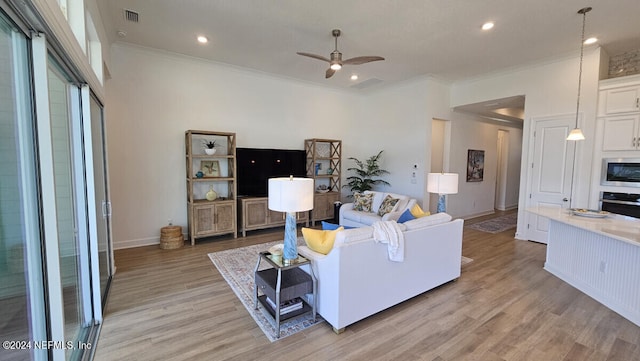 living room featuring ornamental molding, ceiling fan, and light hardwood / wood-style flooring