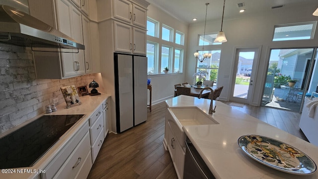 kitchen featuring hanging light fixtures, a notable chandelier, wall chimney range hood, appliances with stainless steel finishes, and sink