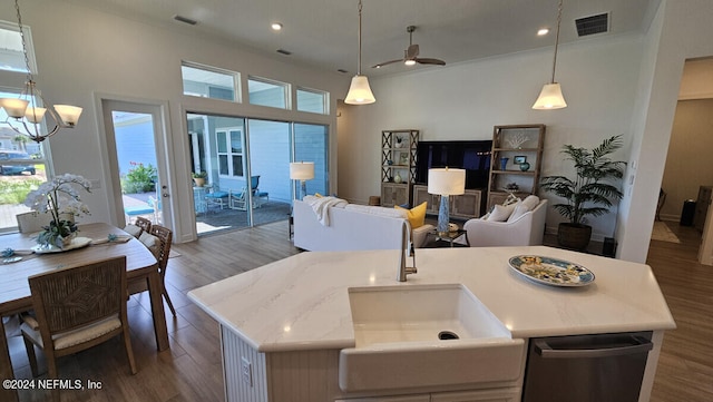 kitchen featuring sink, wood-type flooring, a kitchen island with sink, and hanging light fixtures