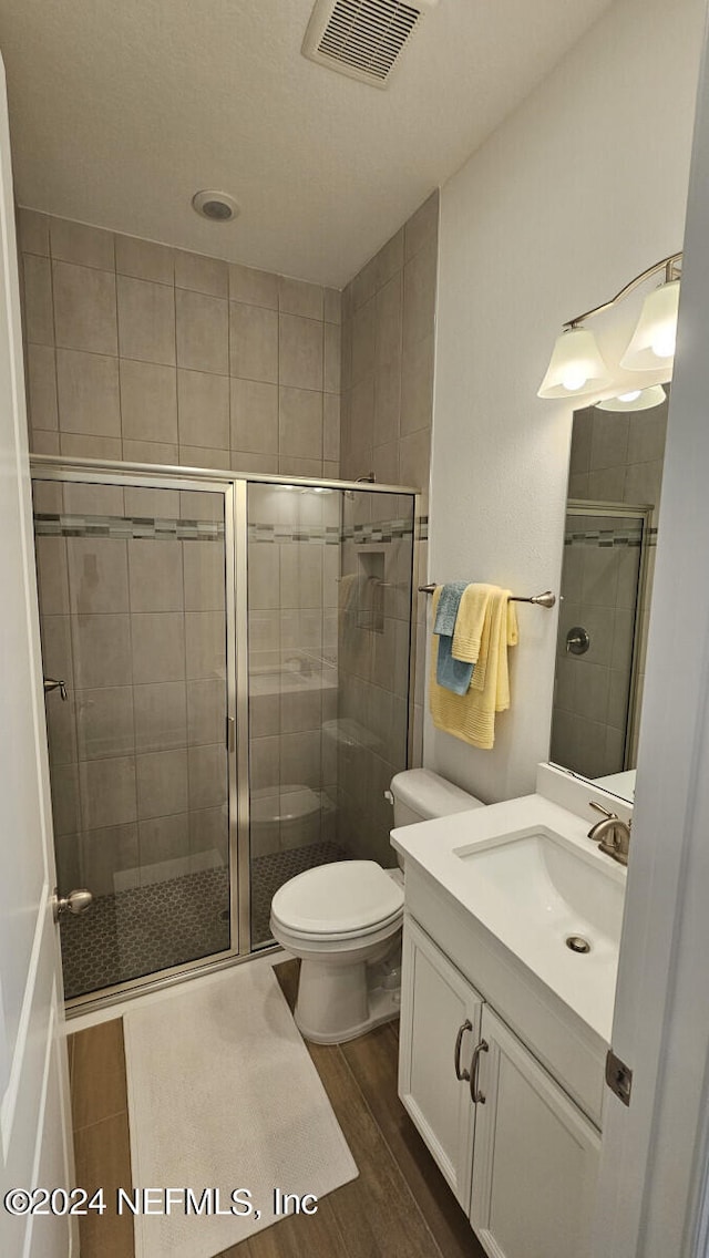 bathroom featuring vanity, walk in shower, toilet, and hardwood / wood-style flooring