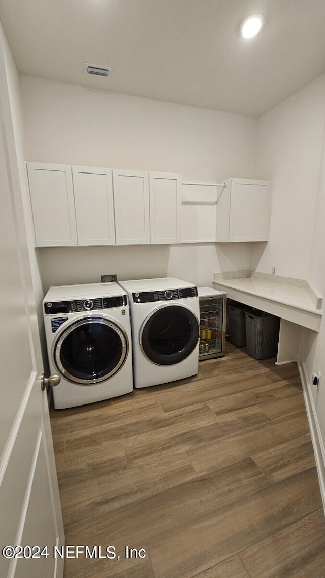 clothes washing area featuring cabinets, washer and clothes dryer, and dark hardwood / wood-style floors