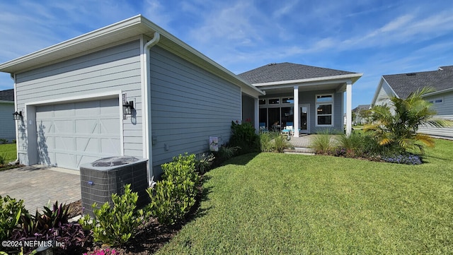 view of front facade featuring covered porch, central air condition unit, a front yard, and a garage