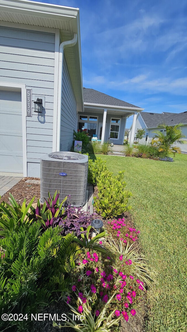 view of home's exterior with a lawn, cooling unit, and a garage