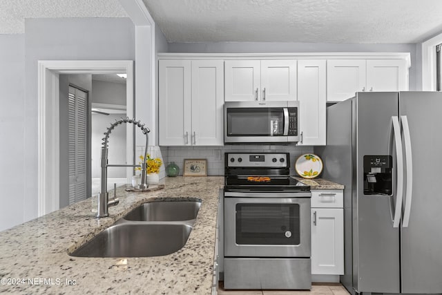 kitchen with sink, decorative backsplash, white cabinets, and appliances with stainless steel finishes