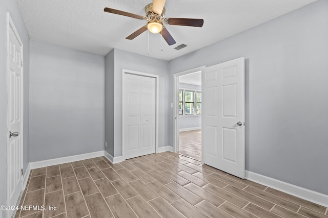 unfurnished bedroom featuring light hardwood / wood-style floors, a textured ceiling, ceiling fan, and a closet