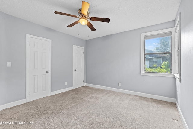 carpeted empty room featuring ceiling fan and a textured ceiling