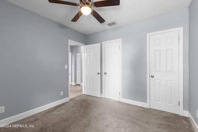 unfurnished bedroom featuring carpet flooring, a textured ceiling, and ceiling fan