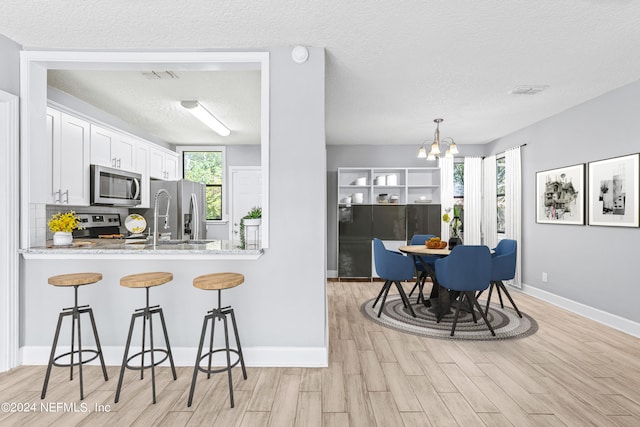 kitchen featuring plenty of natural light, appliances with stainless steel finishes, light hardwood / wood-style flooring, and white cabinets