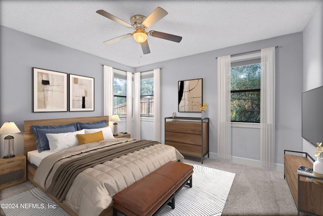 bedroom with light carpet, a textured ceiling, multiple windows, and ceiling fan