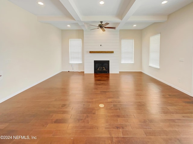 unfurnished living room with beam ceiling, coffered ceiling, a fireplace, and hardwood / wood-style flooring