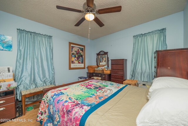 bedroom with wood-type flooring, ceiling fan, and a textured ceiling