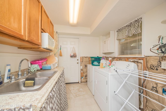 laundry area featuring separate washer and dryer, sink, and cabinets