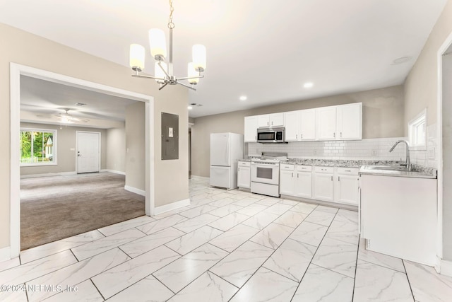 kitchen featuring hanging light fixtures, sink, white appliances, white cabinetry, and light carpet