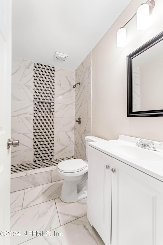 bathroom featuring toilet, vanity, and tiled shower