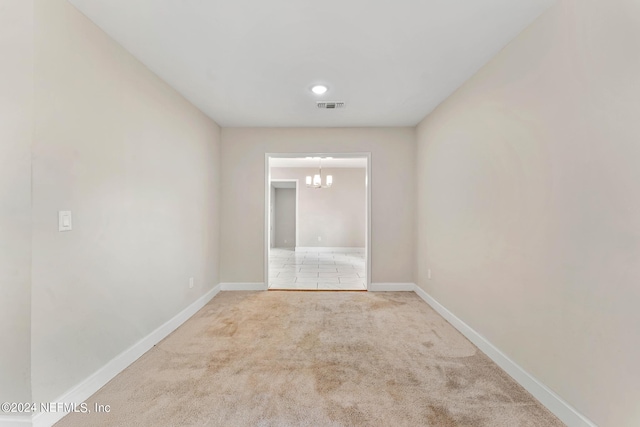 spare room with carpet floors and an inviting chandelier