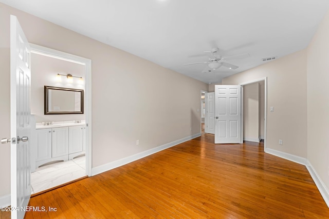 unfurnished bedroom with ceiling fan, hardwood / wood-style flooring, ensuite bathroom, and sink