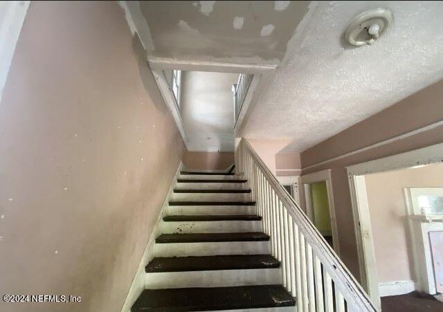 stairway featuring a textured ceiling