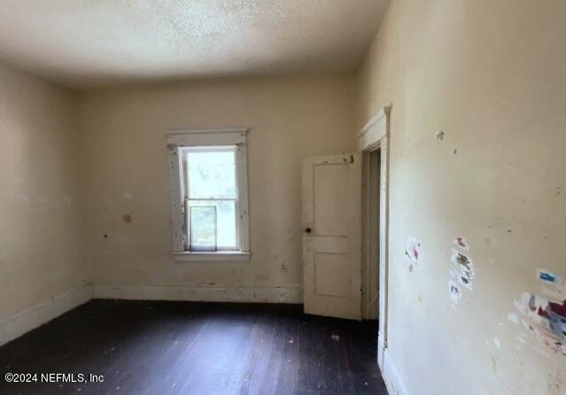 unfurnished room with dark wood-type flooring and a textured ceiling