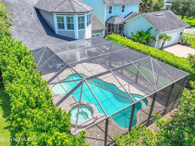 outdoor pool featuring an in ground hot tub, a patio area, and glass enclosure