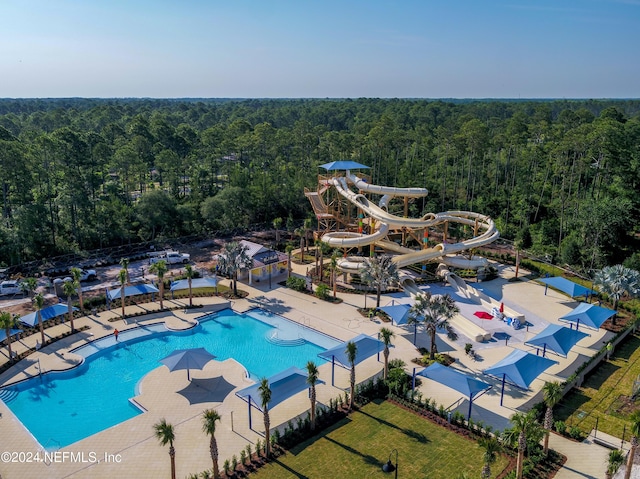 view of swimming pool featuring a water slide and a view of trees