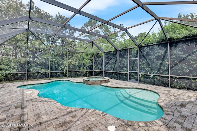 view of pool with glass enclosure, a pool with connected hot tub, and a patio