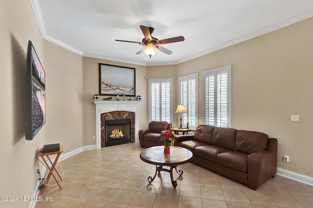 living area with crown molding, a high end fireplace, light tile patterned flooring, ceiling fan, and a textured ceiling