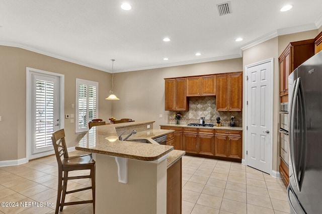 kitchen with light tile patterned floors, visible vents, a kitchen breakfast bar, appliances with stainless steel finishes, and decorative light fixtures