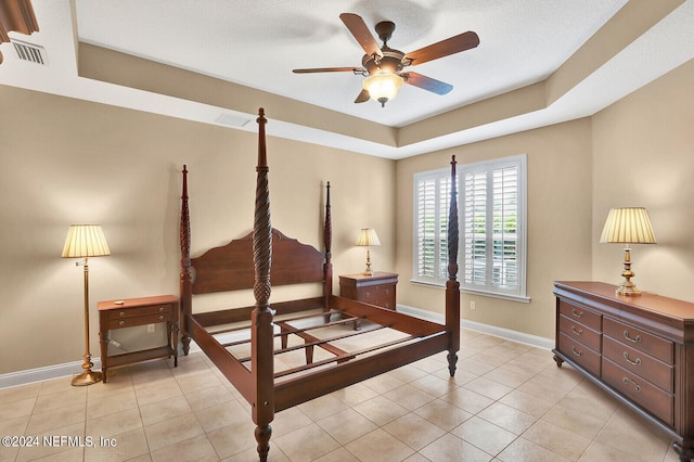 bedroom with light tile patterned floors, a raised ceiling, visible vents, ceiling fan, and baseboards