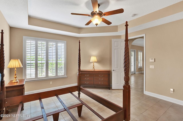 bedroom featuring light tile patterned floors, baseboards, and arched walkways