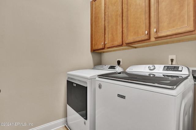 washroom with baseboards, cabinet space, and washing machine and clothes dryer