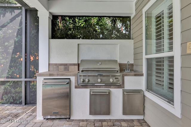 view of patio with exterior kitchen, a sink, and area for grilling