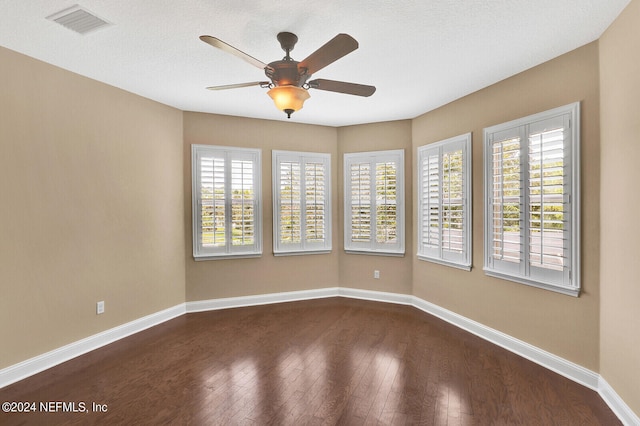 empty room featuring hardwood / wood-style floors, visible vents, and baseboards