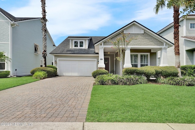 craftsman house featuring roof with shingles, a front lawn, decorative driveway, and an attached garage