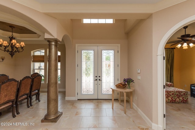 foyer featuring arched walkways, baseboards, french doors, ornate columns, and crown molding