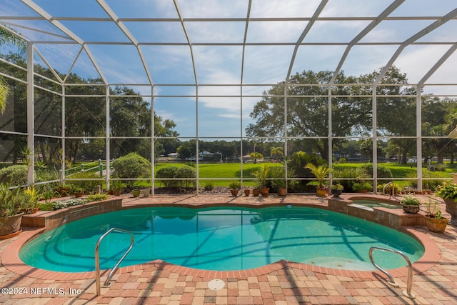 view of swimming pool featuring glass enclosure and a pool with connected hot tub