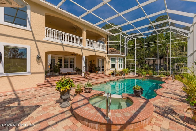 view of pool featuring a lanai, a patio area, a pool with connected hot tub, and a ceiling fan