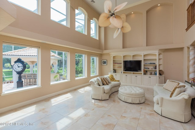 living area featuring a ceiling fan, a healthy amount of sunlight, and baseboards