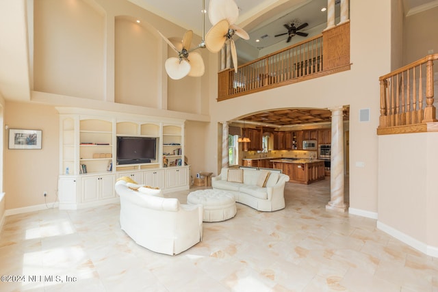 living area with ceiling fan, visible vents, decorative columns, and baseboards