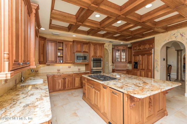 kitchen featuring built in appliances, a sink, arched walkways, and brown cabinets