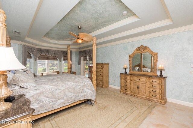 bedroom featuring ceiling fan, visible vents, baseboards, ornamental molding, and a raised ceiling