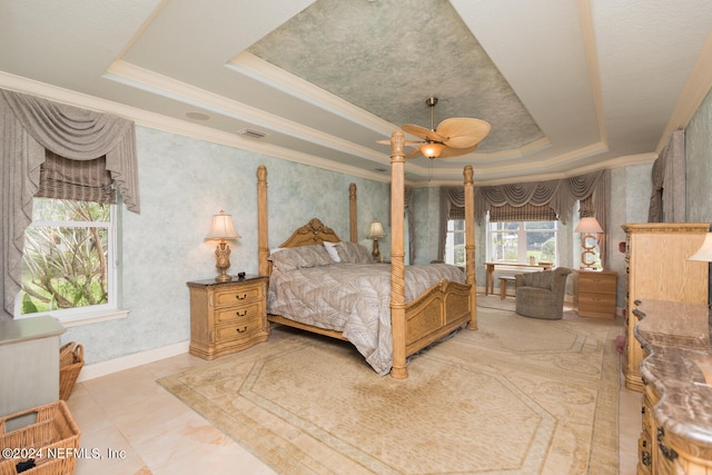 bedroom with baseboards, visible vents, a ceiling fan, a raised ceiling, and crown molding