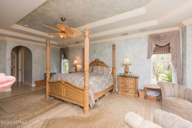 bedroom with arched walkways, a raised ceiling, and crown molding