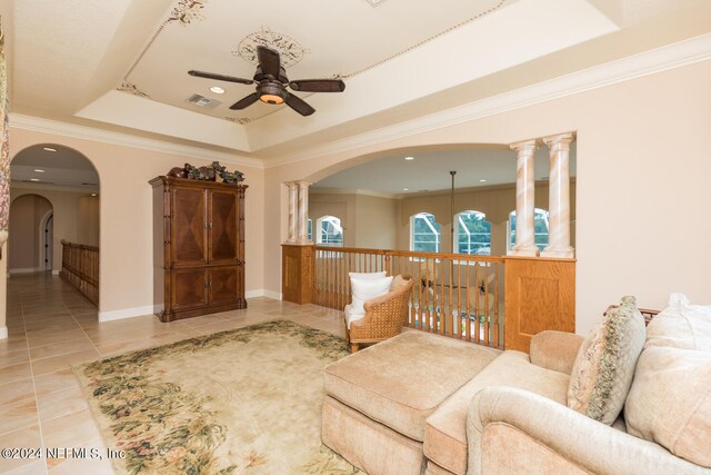 living area with ceiling fan, tile patterned flooring, visible vents, a raised ceiling, and crown molding