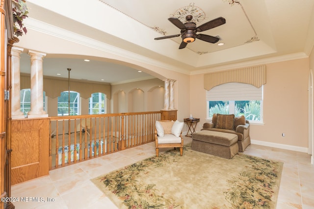 living area featuring ornamental molding, a raised ceiling, decorative columns, and tile patterned floors