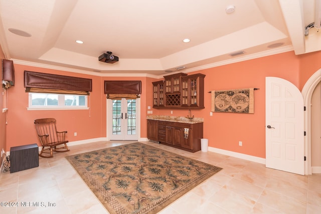 interior space featuring arched walkways, a raised ceiling, baseboards, and french doors