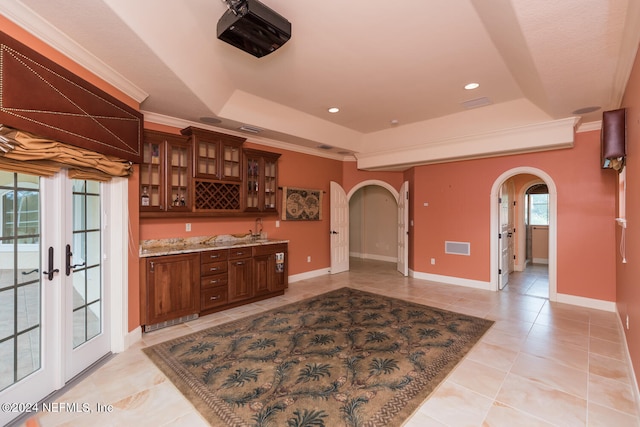 bar featuring ornamental molding, arched walkways, a raised ceiling, and baseboards